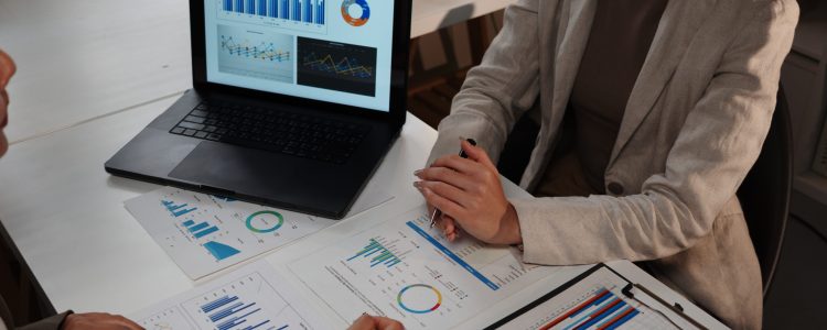 Business team working with data analyzing charts and graphs discussing project strategy using laptop at night in office